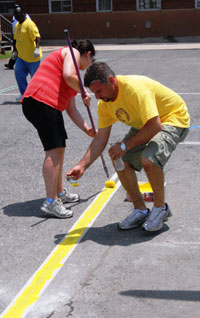 Volunteers paint boundary lines on Esperanza&rsquo;s new basketball court. 